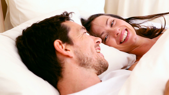 Happy Couple Lying In Bed Chatting