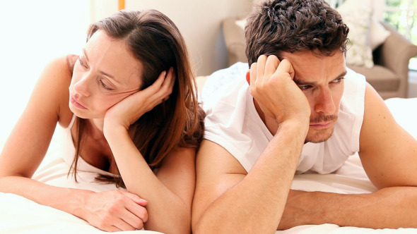 Unhappy Couple Lying On Bed Not Talking