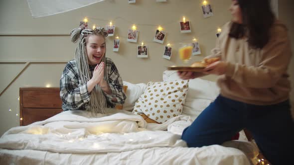 A Young Woman Brings Breakfast To Her Girlfriend in Bed and She Kisses Her on the Cheek