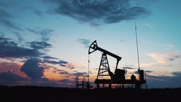Silhouette Working Oil Pump in Deserted District at Sunset