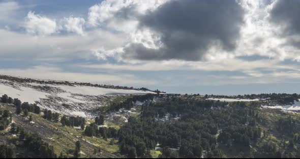 Time Lapse of Cloudscape Behind of the Mountains Top. Snow, Rocks, Cliffs and Deep Blue Sky