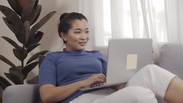 New normal businesswoman work from home by laptop sitting on the sofa happily