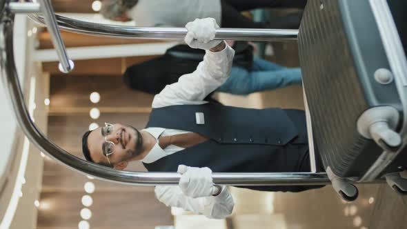 Bellboy Carrying Baggage Cart through Lobby