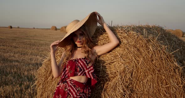 Seductive Girl Touches A Straw Hat At Sunset