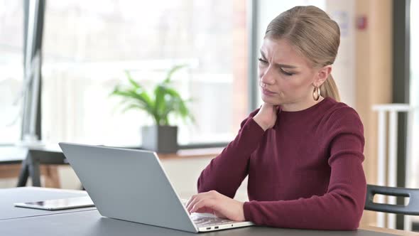 Young Woman with Neck Pain Using Laptop in Office 