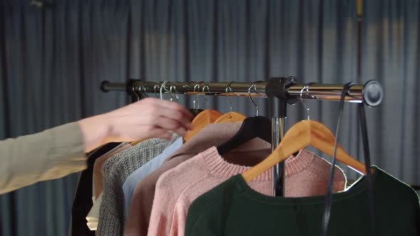 Close Up of Woman Takes a Pink Sweater From a Hanger with Clothes