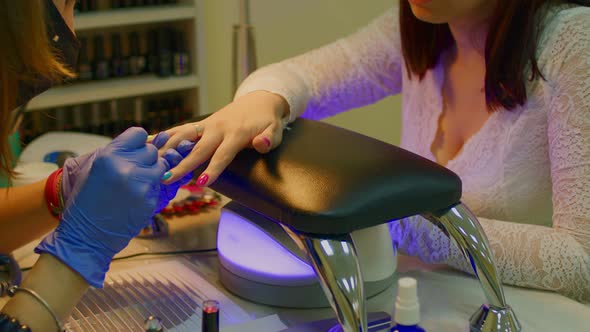 Master of Manicure Getting Professional Manicure in Beauty Salon Woman Puts Nail Polish