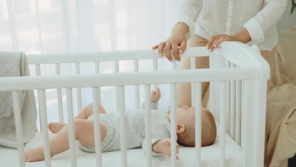 Close View of the Woman Hands Rocking the Baby Cot with Newborn Baby Inside Wearing Cute Baby