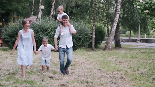 Family with Two Sons Is Walking Together in the Summer Park
