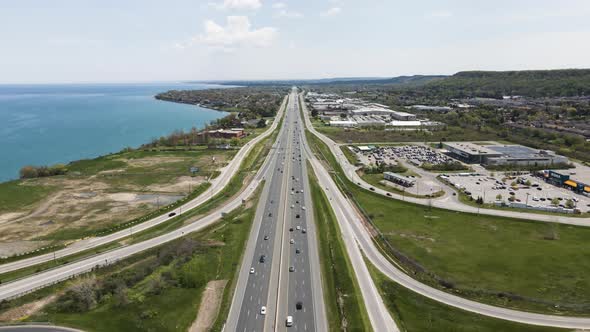 Aerial flyover traffic on highway beside Lake Ontario in Canada during sunny day.