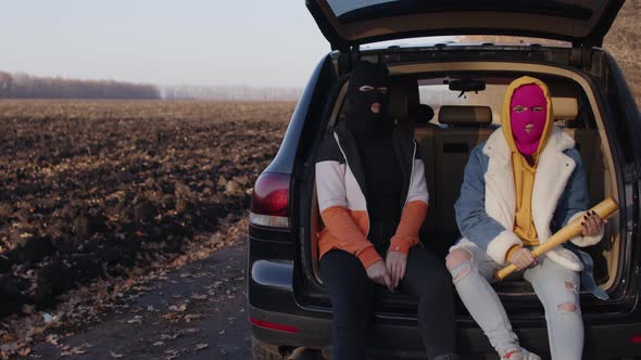 Women in Balaclava Sitting in Trunk of Car