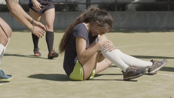 Female Football Player Holding Onto Injured Leg at Stadium