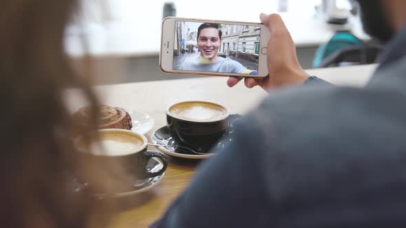 Mobile video calling. Phone with face on screen in hands closeup