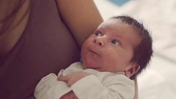 Newborn baby boy and his mother at home. Close-up portrait of the infant