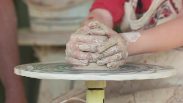 Potter Teaching a Young Child To Make a Clay Pot.