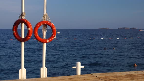 Lifebuoys Hang on a Pole in the Sea, People Are Bathing