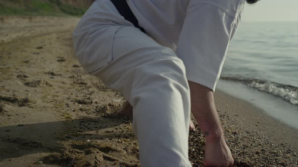 Flexible Athletic Man Stretching on Sand Close Up