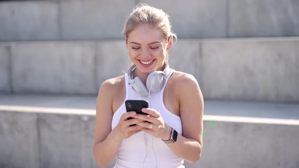 Cheerful Sportswoman Using Smartphone on Street