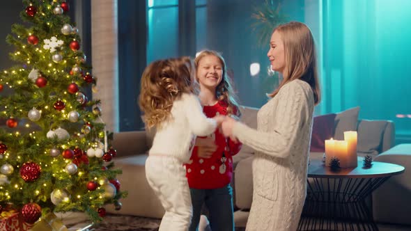 Happy Mother Playing with Daughters Near Christmas Tree