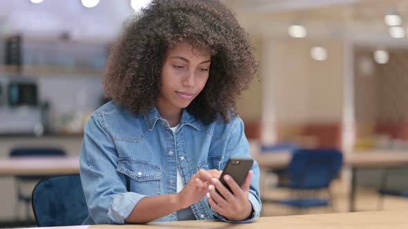 Excited African Woman Celebrating Success on Smartphone at Work 