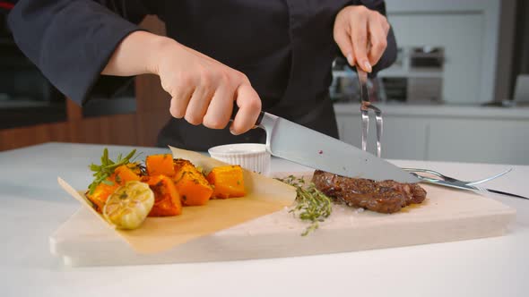 Close Up of Chef Cutting Beef Steak Served with Baked Spiced Pumpkin on