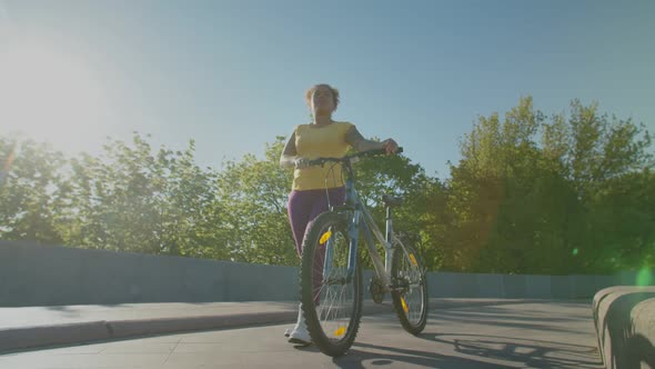 Joyful Active Black Female with Bicycle Walking in City at Daybreak