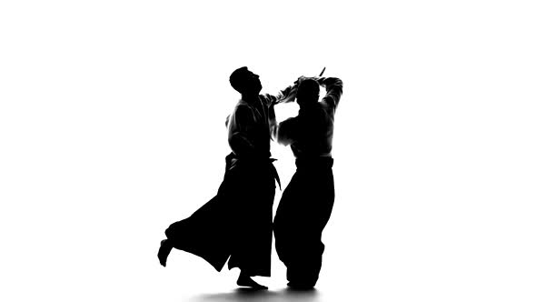 Black Silhuettes of Two Males in Keikogi or Kimono Showing Aikido Using Tanto. Isolated, White. Slow