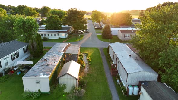 Aerial rising shot of sunset over mobile home park in America. Rural area in USA. Sun shines on smal