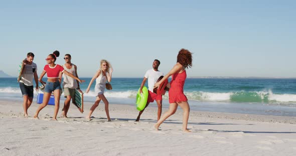 Young adult friends on holiday walking on a beach 4k