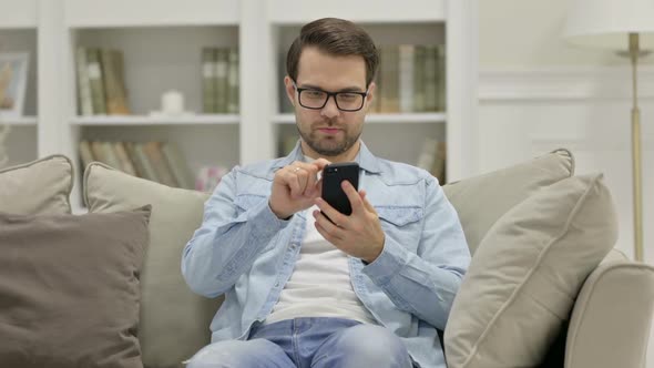 Young Man Using Smartphone at Home