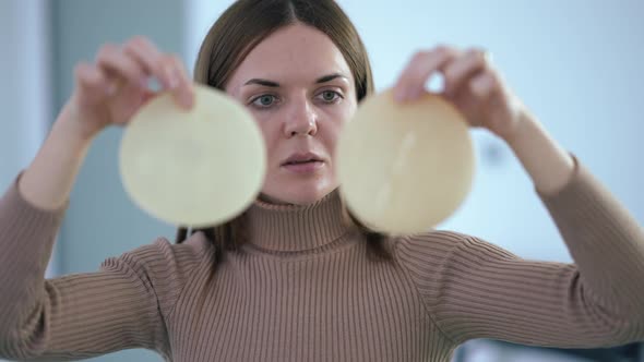 Portrait of Young Caucasian Beautiful Woman Examining Breast Implants Talking