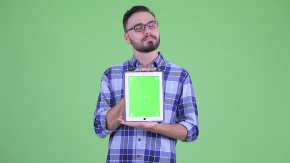 Happy Young Bearded Hipster Man Thinking While Showing Digital Tablet