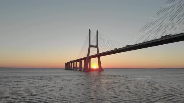 Evocative setting golden sun over Tago river behind Vasco da Gama Bridge