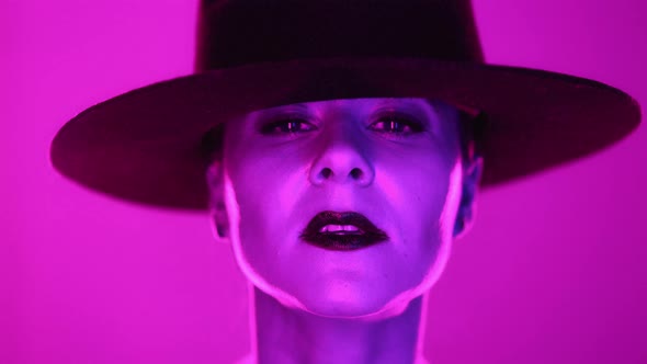 Pink Neon Portrait of Adult Woman in Hat in Violet Studio