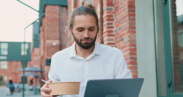 Business Man Eating Takeaway Healthy Food Outdoors and Using Laptop