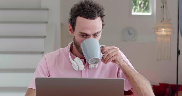 Front View of a Young Multitasking European Guy Entrepreneur Copywriter Journalist Drinking Hot