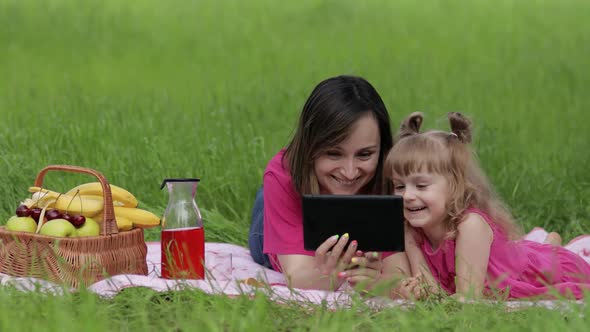 Family Weekend Picnic. Daughter Child Girl with Mother Play Online Games on Tablet. Chatting