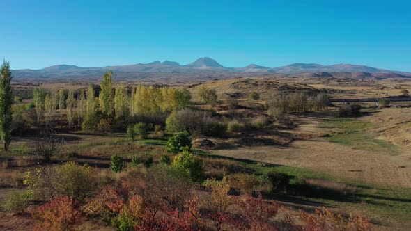 Aerial Drone Shot Zoom in of Fields and Trees on Background of Mount Aragats