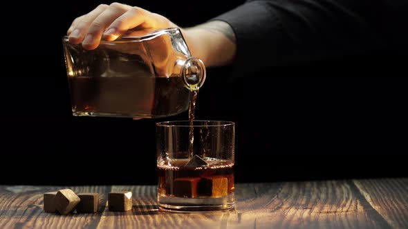 Pouring Whiskey, Cognac Into Glass. Black Background. Pour of Alcohol Drink