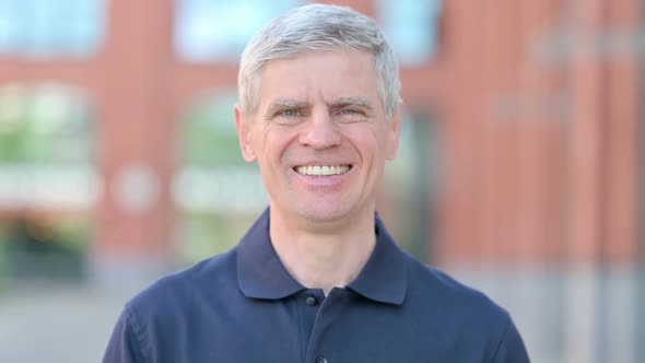 Outdoor Portrait of Cheerful Middle Aged Man Smiling at Camera