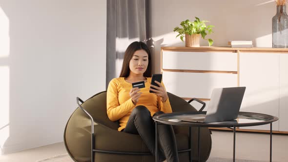 Japanese Woman Using Smartphone And Credit Card Shopping Indoor