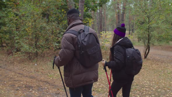 Interracial Couple with Backpacks Trekking in Wood