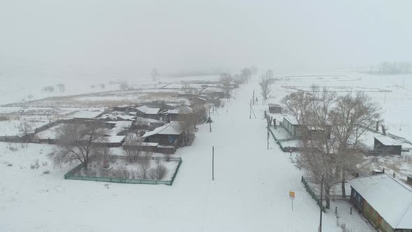 Flying in Snow Over Village