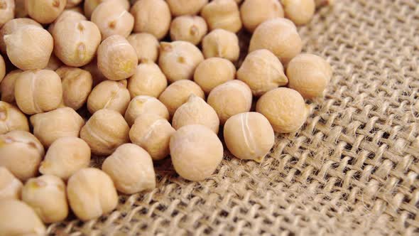 Dry chickpeas, whole chick peas on a rough rustic burlap. Macro. Slow turning