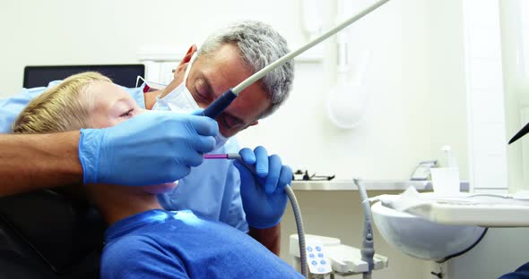 Dentist examining a young patient with tools