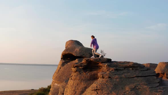 A Girl Does Sports at Sunset on the Shore of the Lake