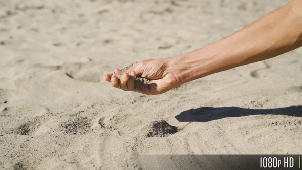 Picking up a handful of sand and moving it through his fingers