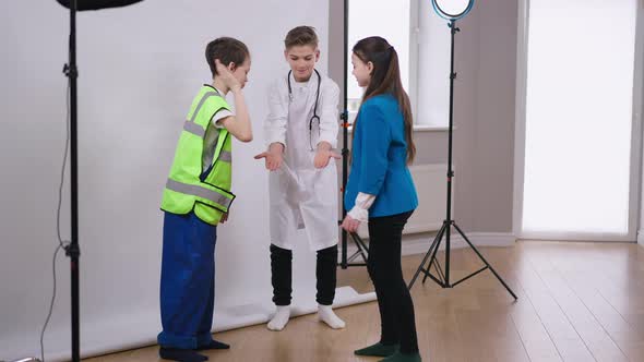 Wide Shot Portrait of Positive Smiling Handsome Teenage Boy in Medical Gown Gesturing Low Five with