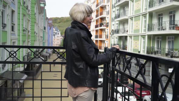 Side View Smiling Confident Senior Woman Standing on Urban Balcony Admiring Beauty of Town Outdoors