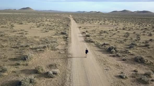 Hopeful rocky road to success. Girl walk on desert alone road.Marvelous aerial view flight pursuit